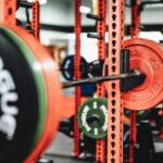Detailed view of a weightlifting setup in a modern gym featuring colorful weight plates on a barbell.