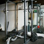 A well-equipped gym featuring a barbell setup with weights and a mirror.